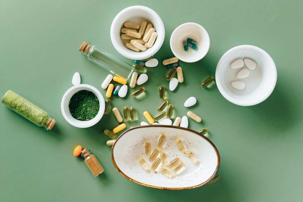 flat-lay-photo-of-alternative-medicines-7615571 Top view of various herbal and pharmaceutical supplements in ceramic bowls on a green background.